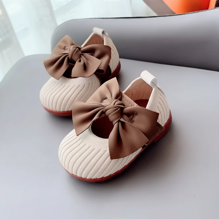 White knitted baby shoes with rounded toes and oversized brown bows