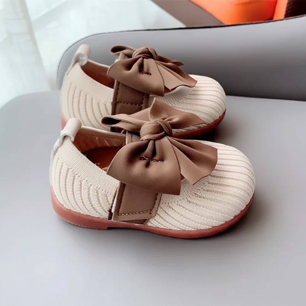 White knitted baby shoes showing bow-topped straps and closed rounded toes