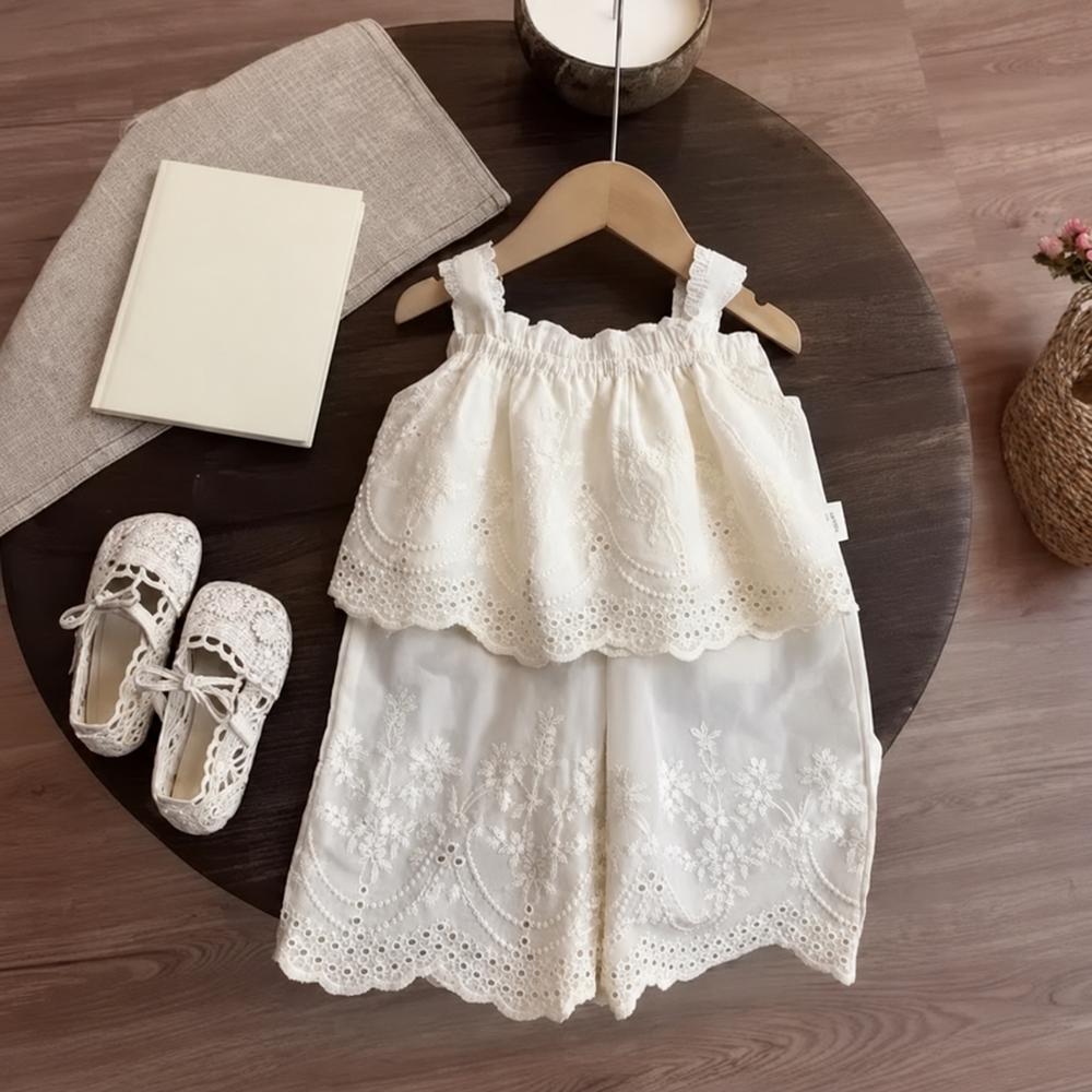 White lace top on a hanger layered over matching embroidered wide-leg pants