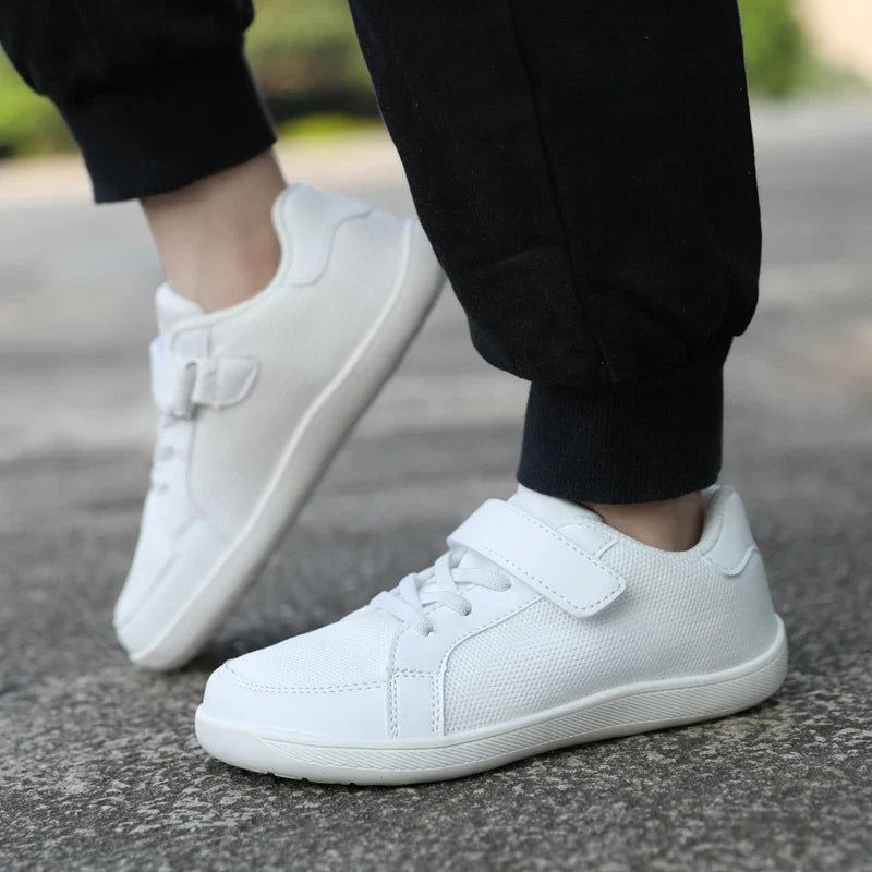 Side view of white low-top sneakers worn outdoors with black pants