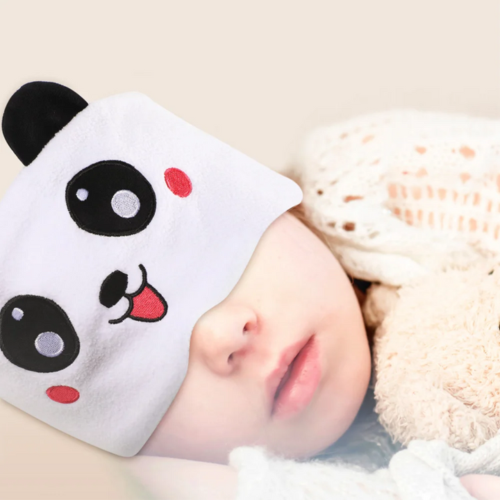 Child resting in bed while wearing the white panda Bluetooth sleep mask.