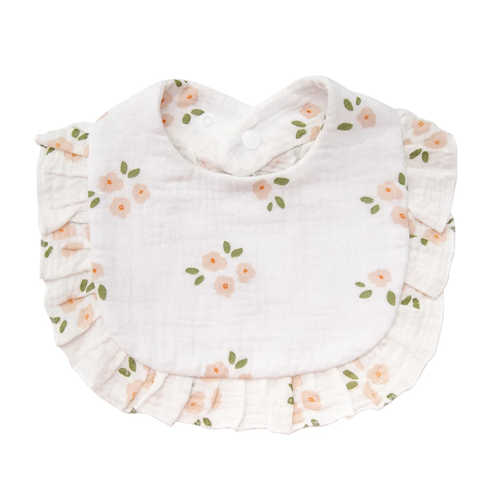 White cotton baby bib with peach-colored blossoms, green leaves, and ruffled trim