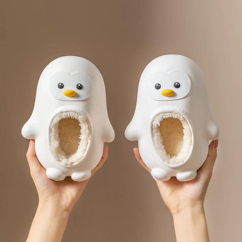 Pair of white penguin slippers held upright to show the faces and lined openings