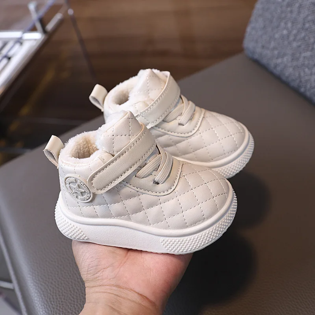 Pair of white quilted winter boots with plush lining held in one hand