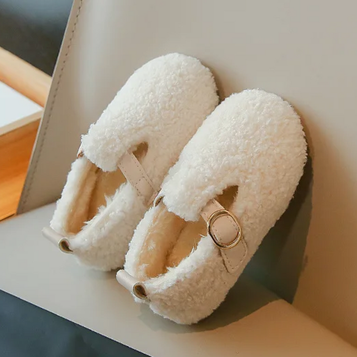 White plush slip-on shoes with rounded toes and round buckle details