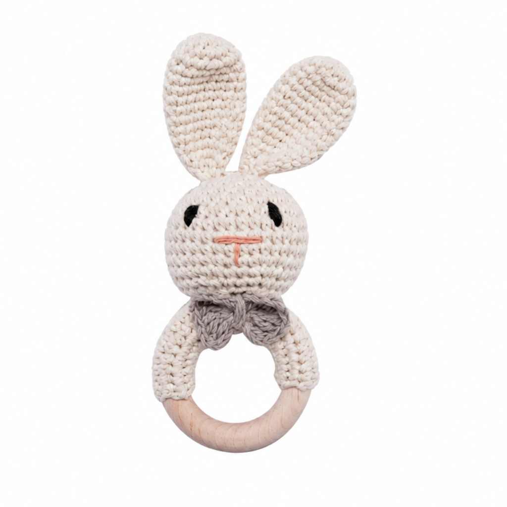 White crocheted rabbit rattle with long ears, a gray bow, and a wooden ring