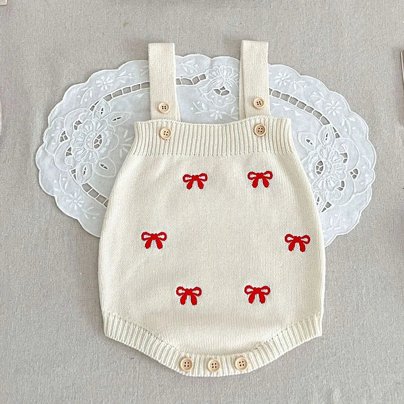 White knit strap bodysuit with red bows and buttons at the shoulders and crotch