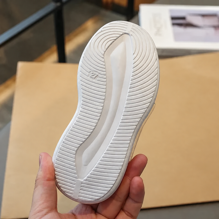 Underside of a white sneaker sole showing curved tread grooves