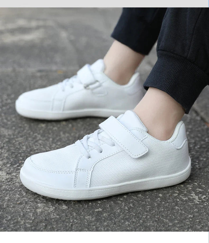 White mesh sneakers worn with black pants, showing the side panels and straps