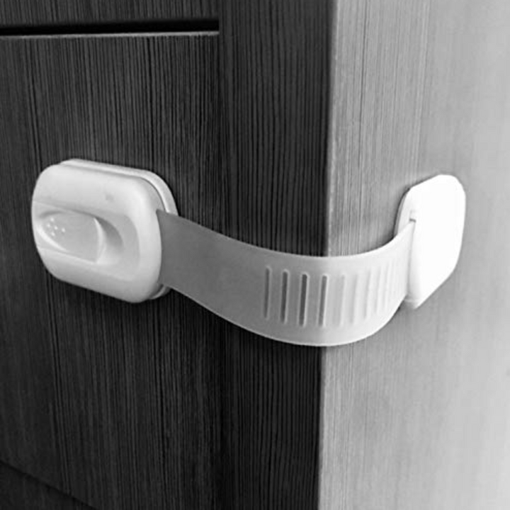White strap lock attached around the corner of a dark wood cabinet