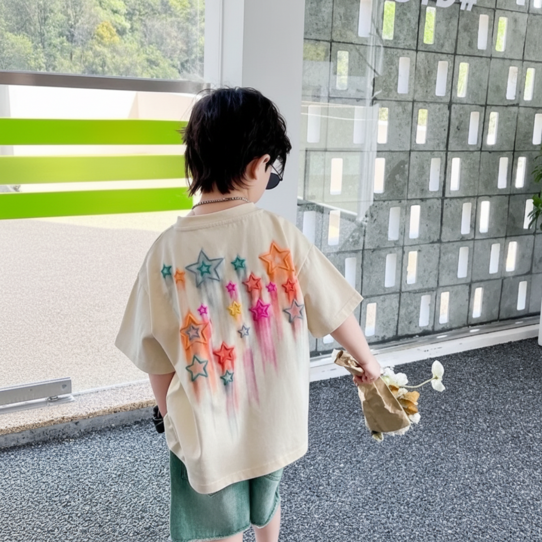 Child wearing a white T-shirt with colorful back star graphics and green shorts