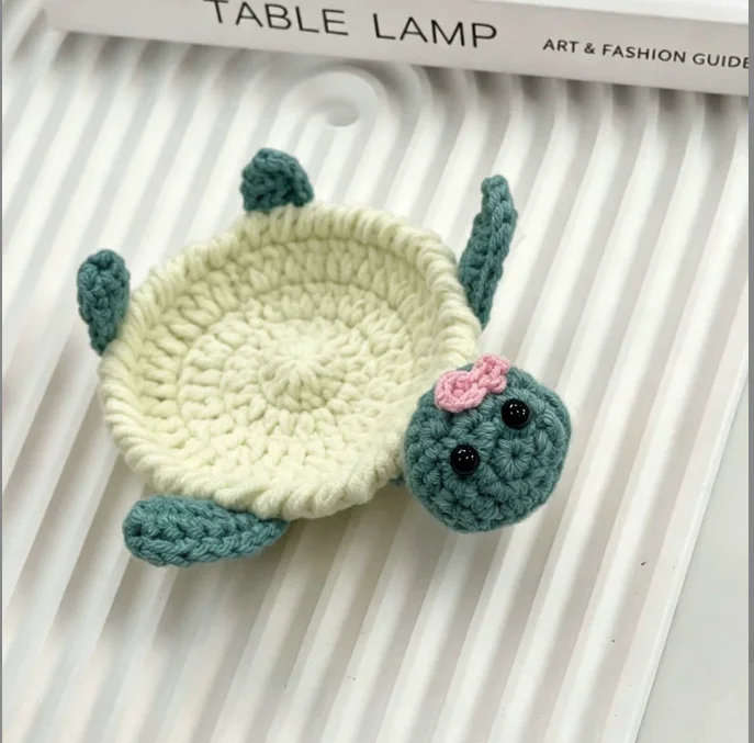 White turtle coaster with a pale center, teal head and flippers, and a pink bow