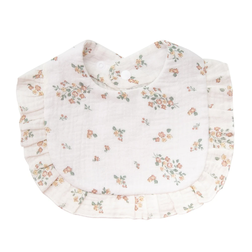 White cotton baby bib with scattered wildflower sprigs and ruffled trim
