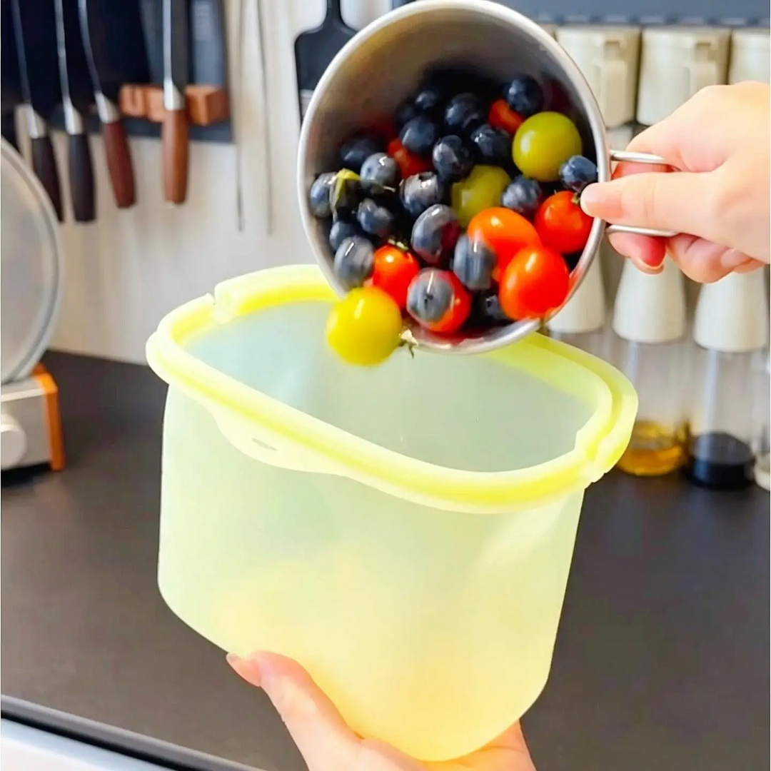 Berries and cherry tomatoes being poured into the wide opening of a silicone food storage bag.