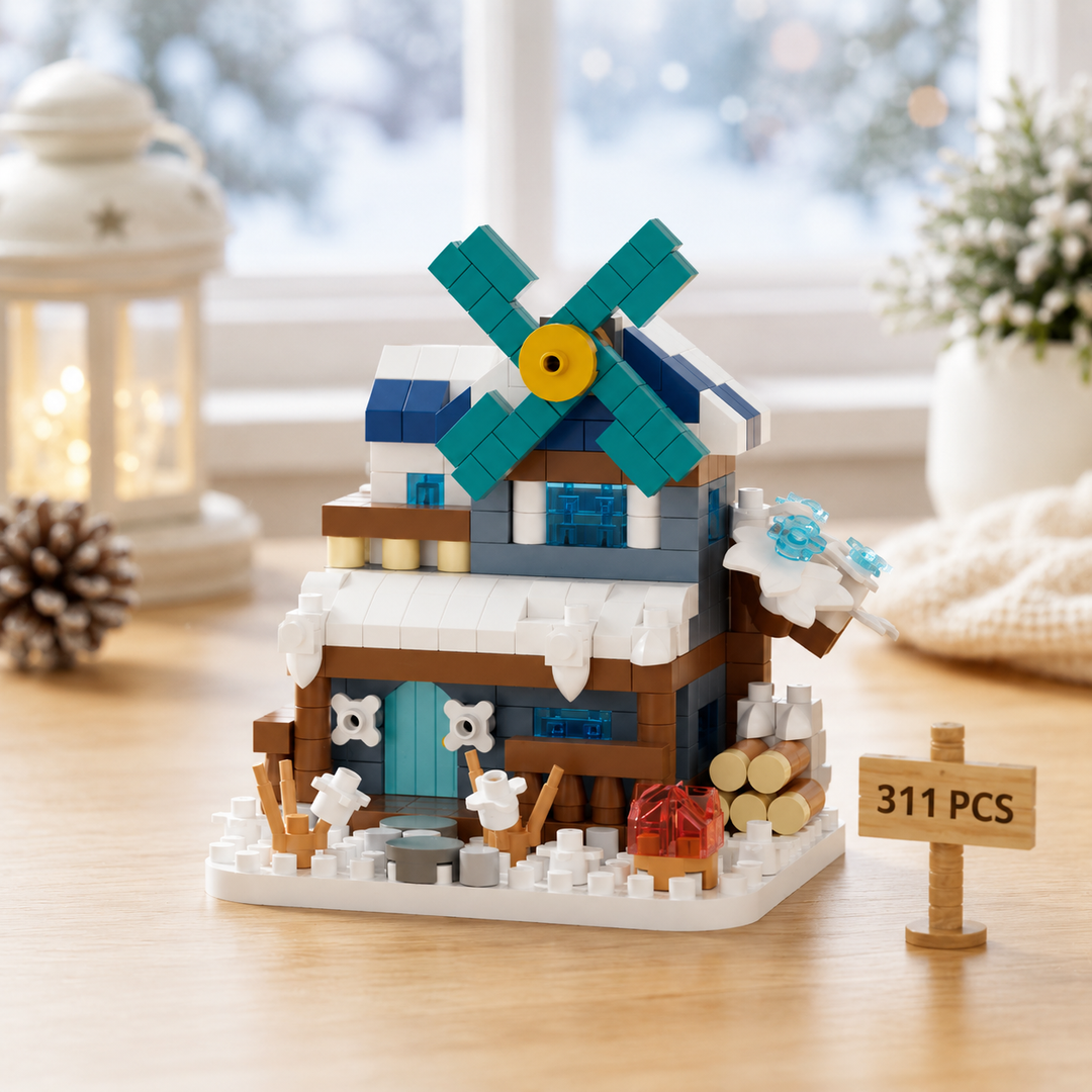 Winter windmill block model with teal blades, a snow-covered roof and miniature trees.