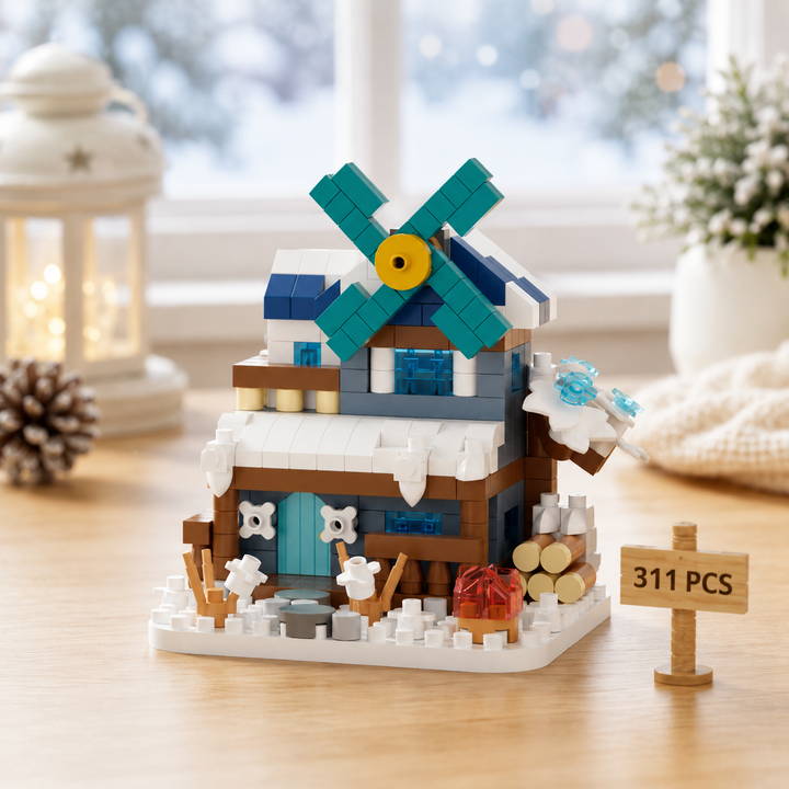 Winter windmill block model with teal blades, a snow-covered roof and miniature trees.