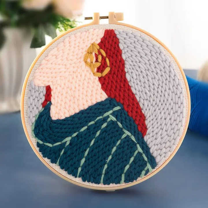 Profile portrait punch needle hoop showing a woman with a gold earring and dark green clothing