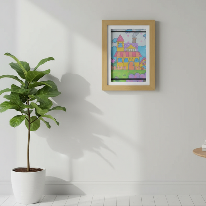 Wood-tone art frame with a colorful castle drawing beside a potted plant