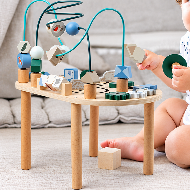 Child playing beside a wooden activity table with blocks, bead tracks, and gears