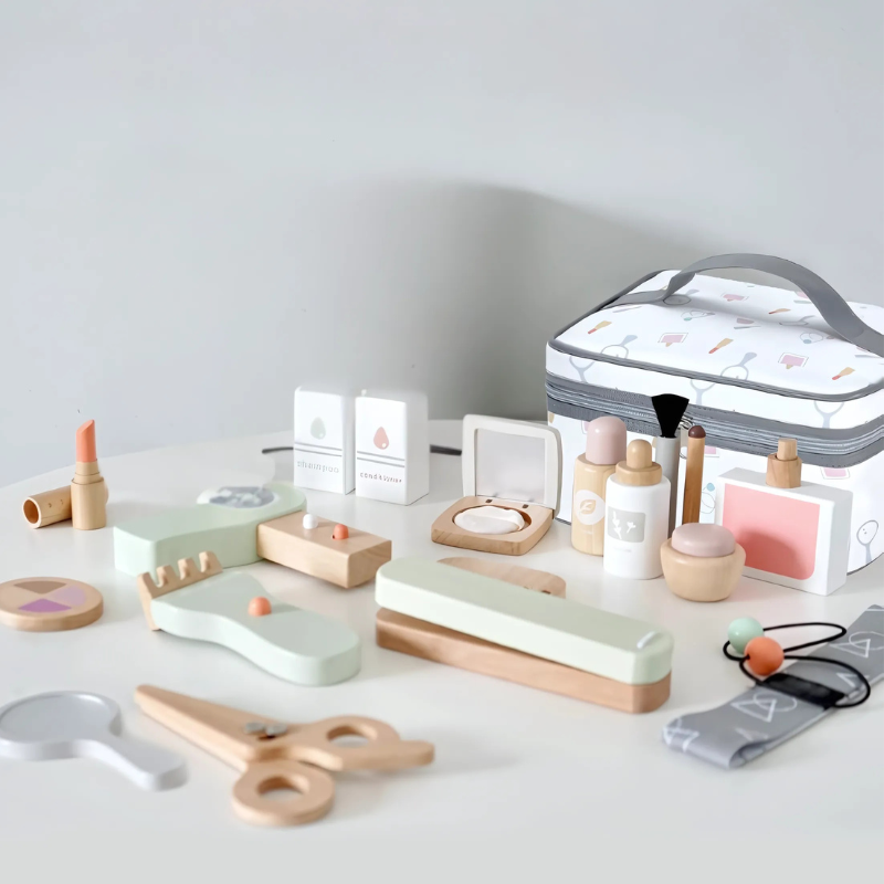 Wooden toy beauty accessories arranged beside a fabric carry bag with handles