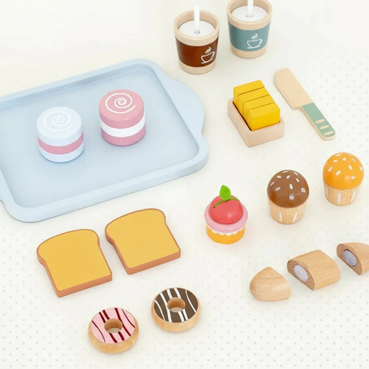 Wooden Breakfast set pieces arranged around a blue tray, including cakes, toast, and cups