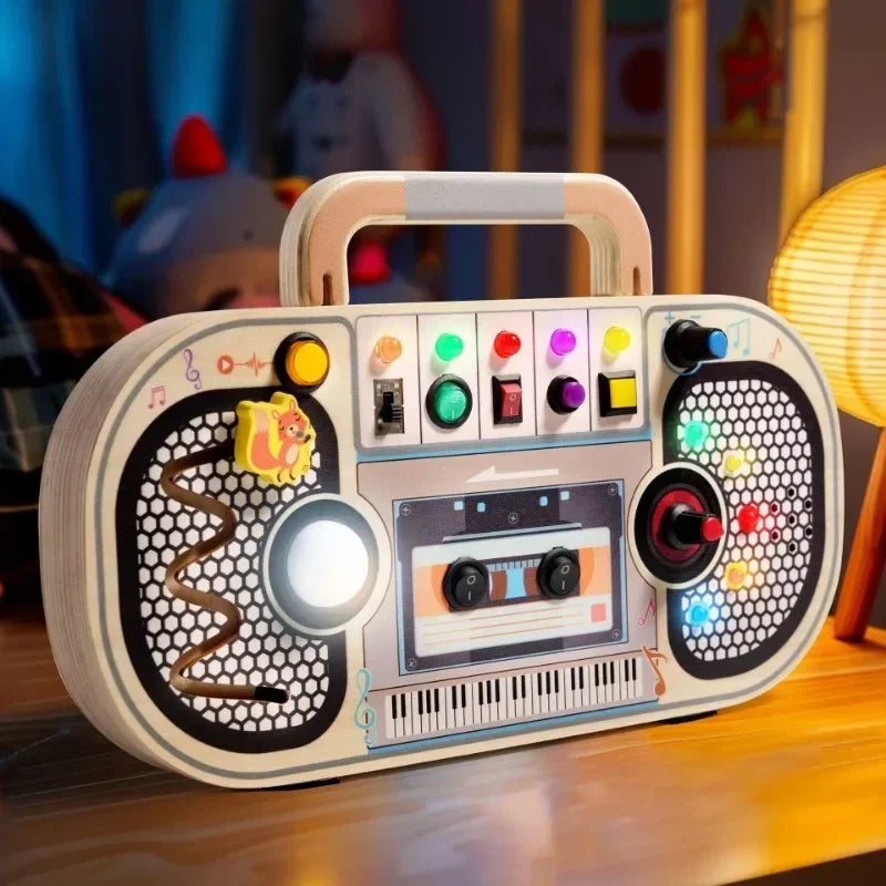 Wooden music busy board with illuminated activity lights on a table beside a lamp