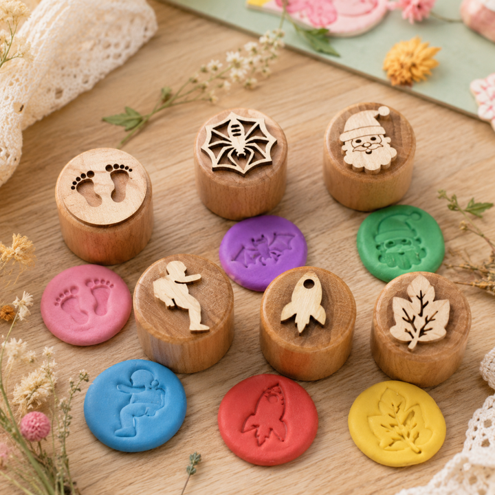 Wooden clay stamps in assorted themes beside colorful dough impressions on a craft table.