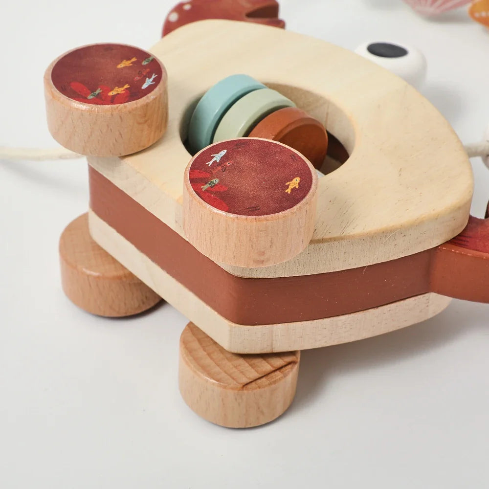 Wooden crab toy lying flat, showing its layered body, wheels, and center discs
