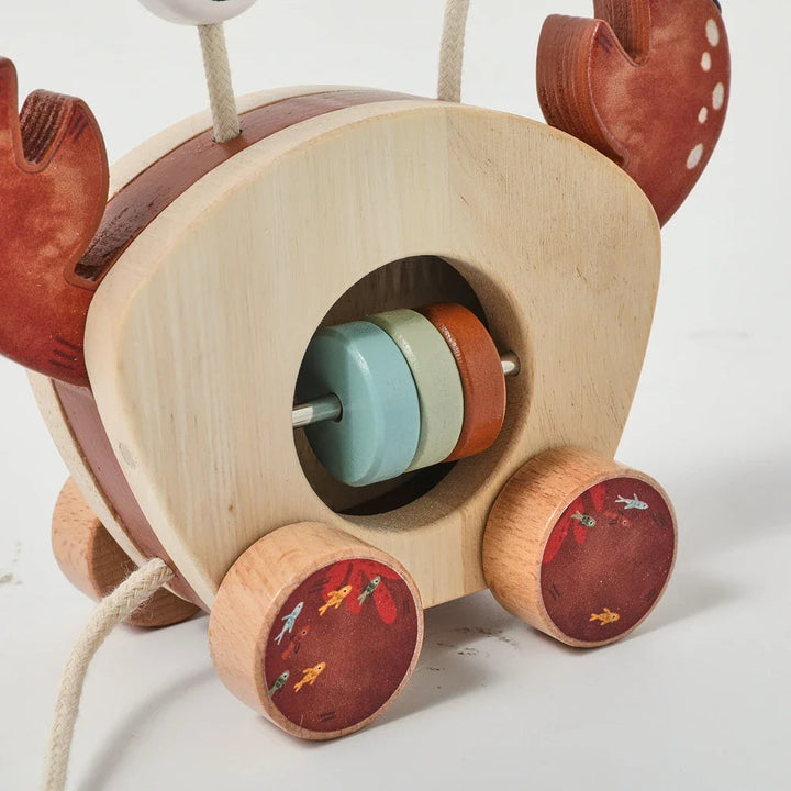 Rear view of the wooden crab toy with colored center discs, wheels, and pull cord