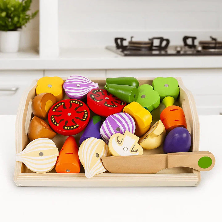 Tray of wooden vegetable pieces with onion halves, tomato slices, and a wooden toy knife