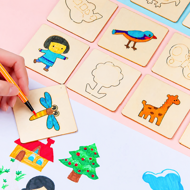 Hand painting a dragonfly on a wooden drawing card beside bird, person, and giraffe designs.