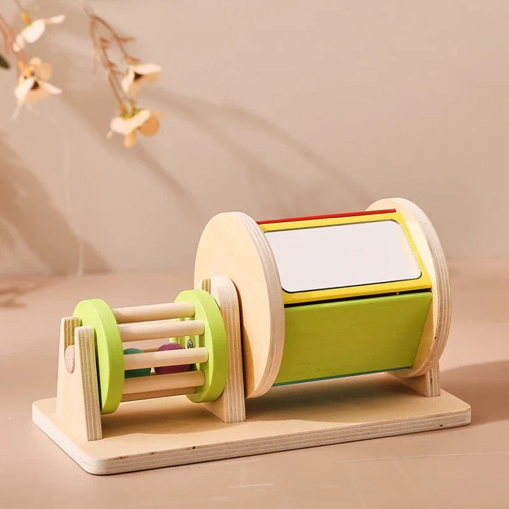 Wooden spinning drum with a white panel and a small rattle mounted on the left