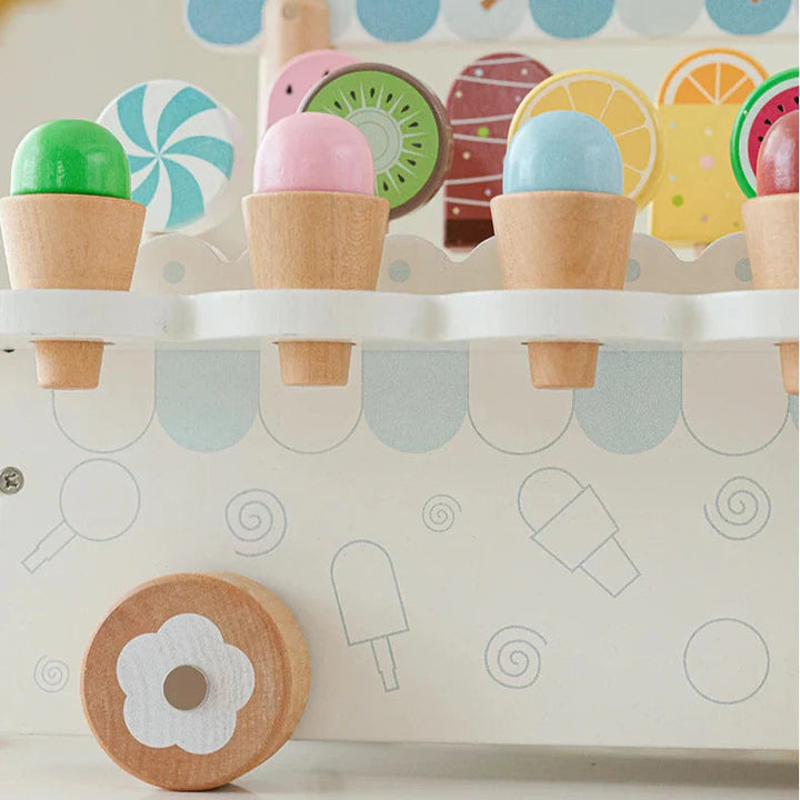 Close-up of colorful wooden ice cream cones in display slots above a flower-centered cart wheel