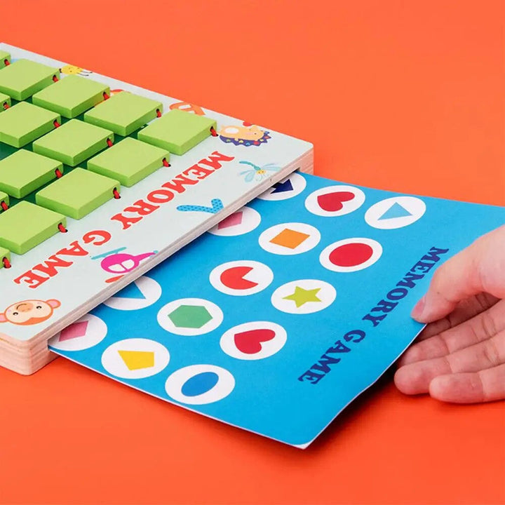 A hand changing a blue card with colorful shapes in the wooden memory game.