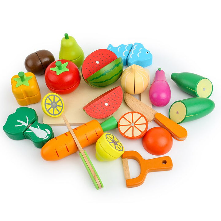 Wooden play foods with separated sections arranged around a cutting board, knives and orange peeler