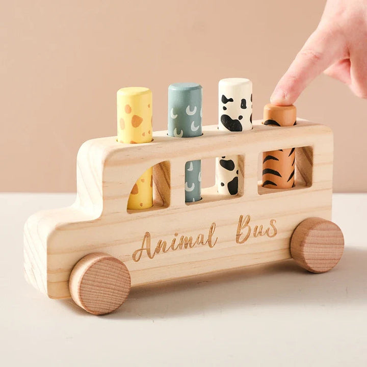 Finger pressing an orange animal-print peg in a wooden toy bus