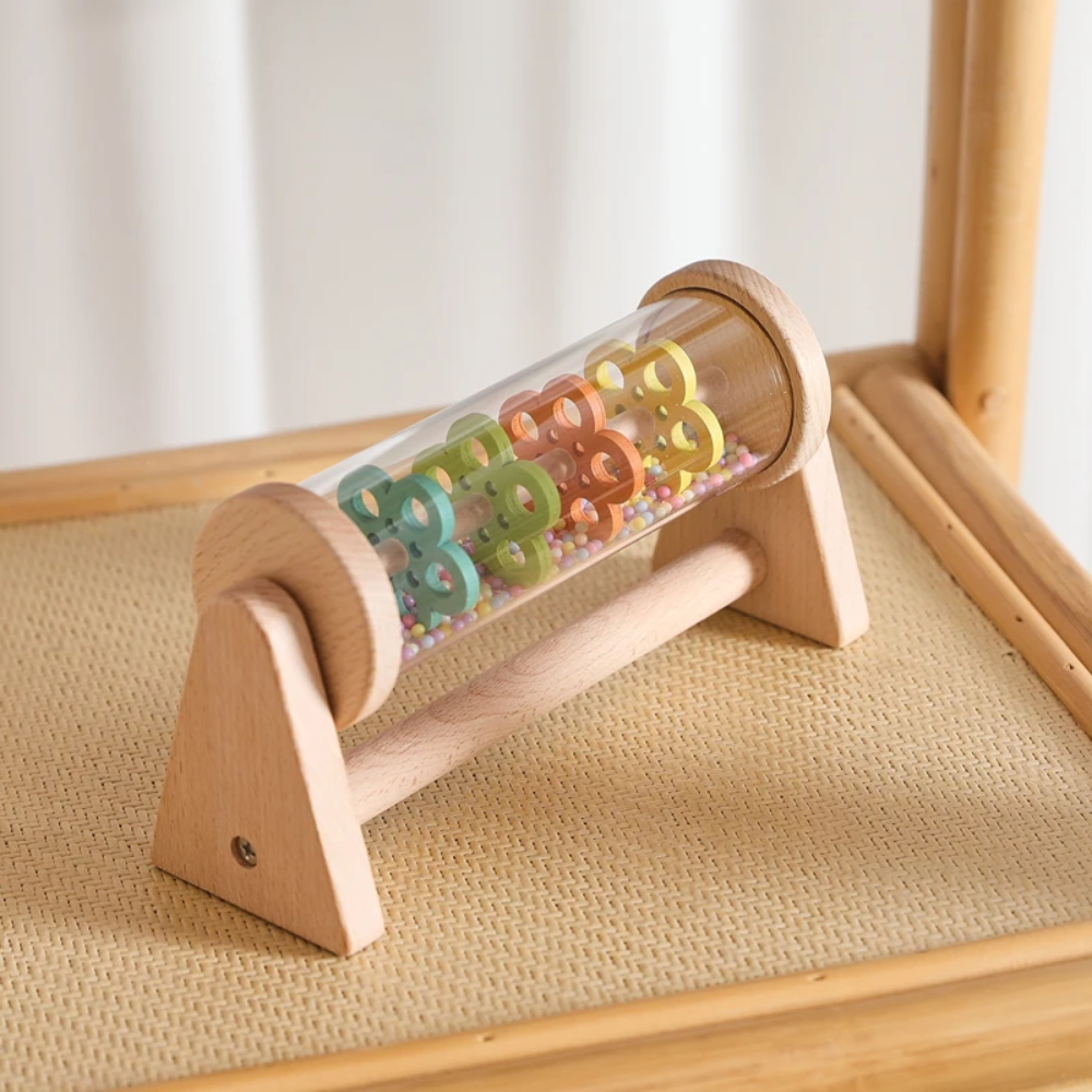 Wooden rain sound toy resting on a woven chair seat.