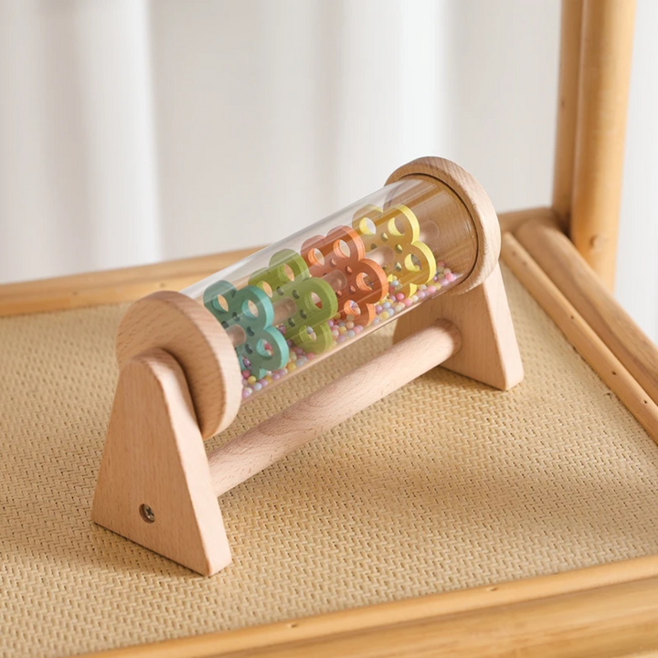 Wooden rain sound toy resting on a woven chair seat.