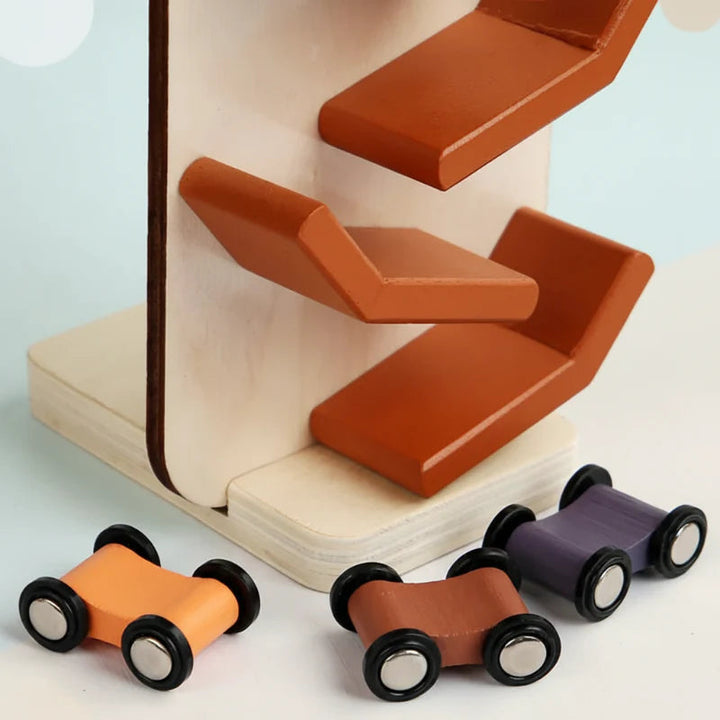 Close-up of orange zigzag ramps, a wooden base, and three colorful toy cars