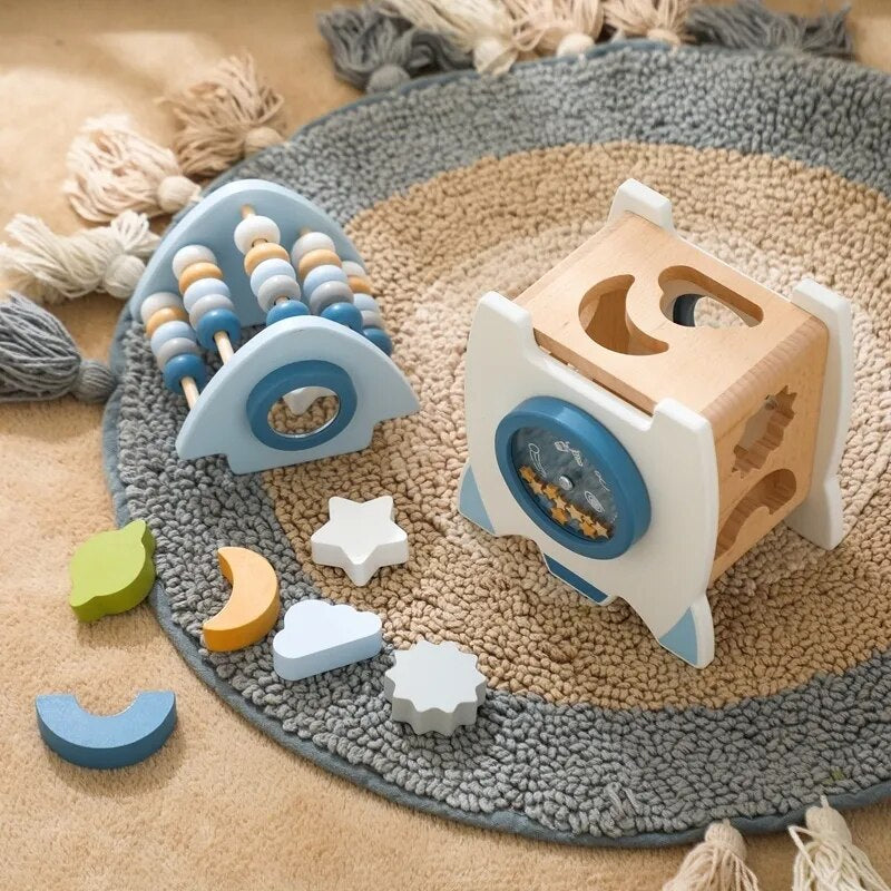 Wooden rocket with its bead top removed and colorful sorting shapes arranged on a rug.
