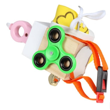 Wooden sensory cube with a green spinner, laces, pink ring, and orange buckle