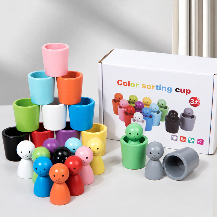 Wooden color-sorting set with smiling figures, stacked cups, and its box