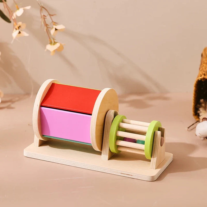 Wooden drum showing red and pink panels beside a green-ended rattle