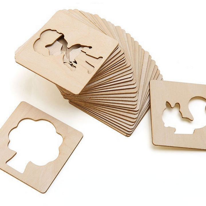 Stacked wooden drawing stencils with person and tree cutouts.