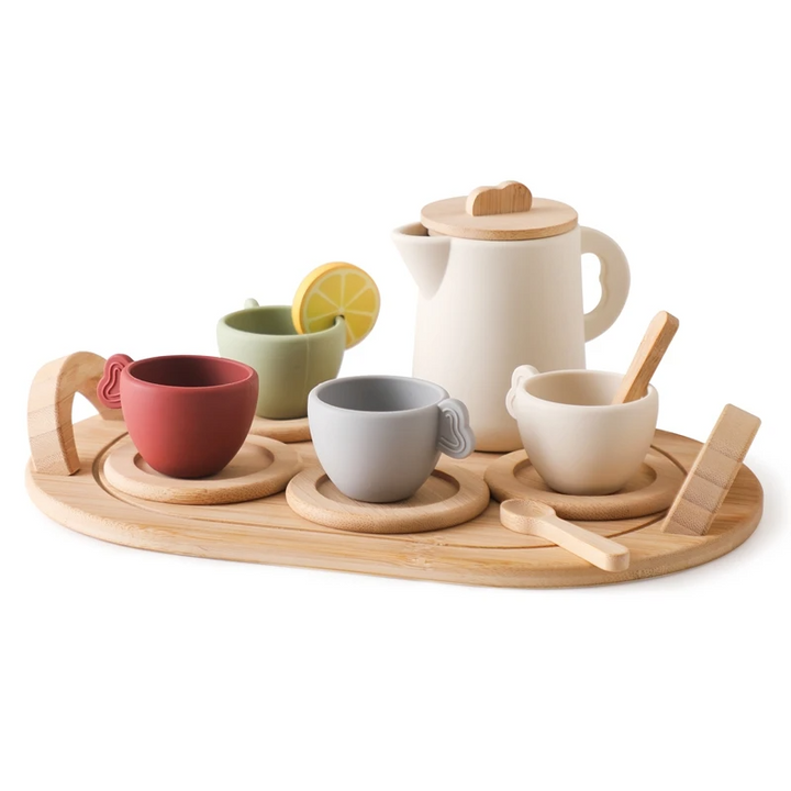 Toy teapot and four cups on a wooden tray with coasters, spoons, and a pretend lemon slice