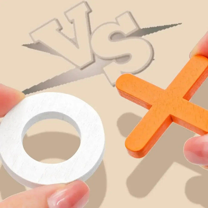 Close-up of an orange wooden X and white wooden O held in two hands