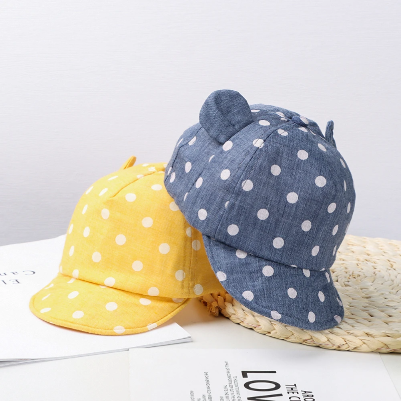 Yellow and navy polka dot caps displayed together beside a woven mat.