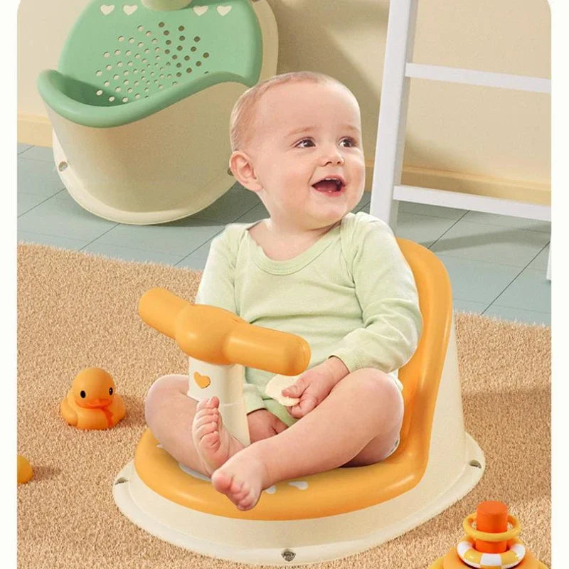 Baby sitting in a yellow bath seat with a green bath seat in the background