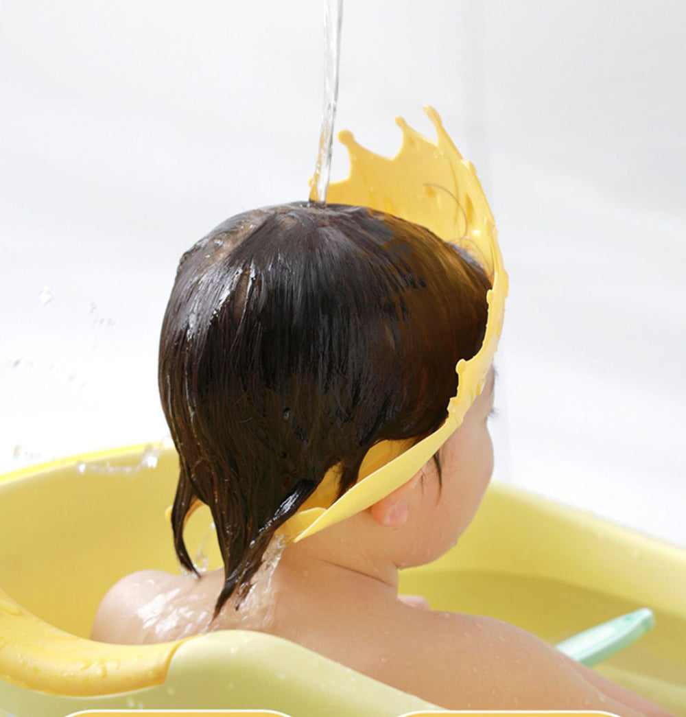 Rear view of a child's hair being rinsed while wearing a yellow crown bath cap