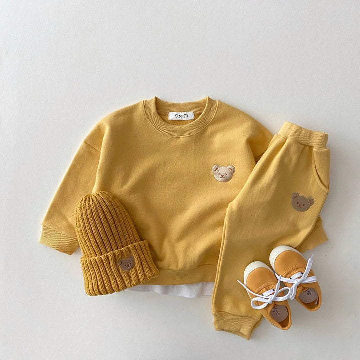 Yellow bear-patch sweatshirt and pants styled with a matching ribbed hat and yellow shoes